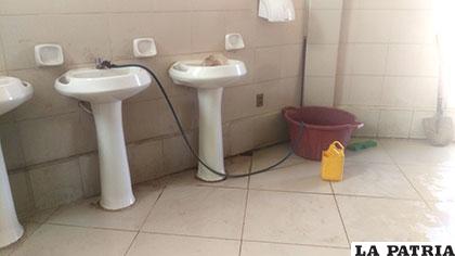 Una manguera y un recipiente son empleados para echar agua en los inodoros