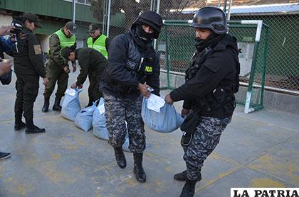 Dos uniformados transportan uno de los sacos de mineral secuestrados