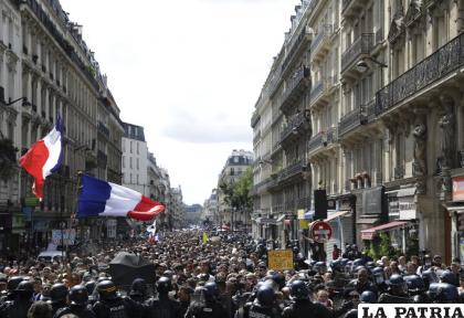Banderas francesas ondean durante una marcha de miles de manifestantes en París (AP Foto/Adrienne Surprenant)