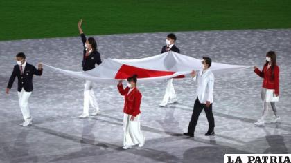 La judoka Takato Naohisa, la nadadora Ohashi Yui, la gimnasta artística Kitazono Takeru, la bailarina de breakdance Kawai Ramu, la modelo Amane y el subdirector médico Yokota Hiroyoki con la bandera japonesa /Getty Images
