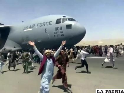 Cientos de personas corren al lado de un avión C-17 de la Fuerza Aérea de EEUU mientras avanza por la pista del aeropuerto internacional de Kabul (UGC verificado, vía AP)