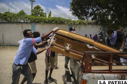 Varios individuos cargan en una camioneta el féretro con el cadáver de Francois Elmay para ser enterrado en un cementerio de Les Cayes /AP Photo /Joseph Odelyn