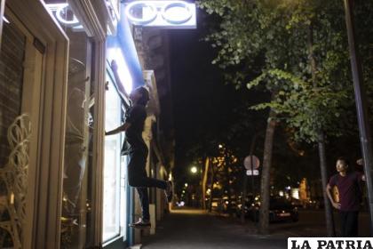Hadj Benhalima, del colectivo “On the Spot”, salta para apagar luces durante una noche de acciones en la que apagarán luces de docenas de escaparates en París /AP