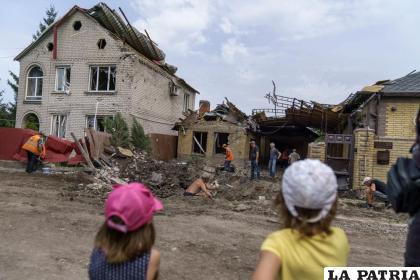 Niños observan a trabajadores que remueven los escombros tras un ataque con cohete a una vivienda en Kramatorsk /AP Foto/David Goldman