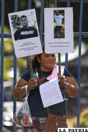 Un manifestante sostiene carteles con las fotografías y los nombres de dos personas detenidas /AP Foto /Salvador Melendez