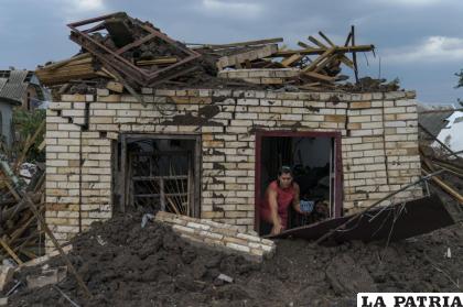 Olga Rudneva, residente de la localidad ucraniana de Druzhkivka, recupera un artículo para un anciano dueño de una casa dañada /AP Foto/David Goldman