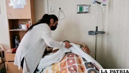 Ingrid, una de las hijas de Mario lo recuesta en la cama del hospital /La Barba del Quirquincho