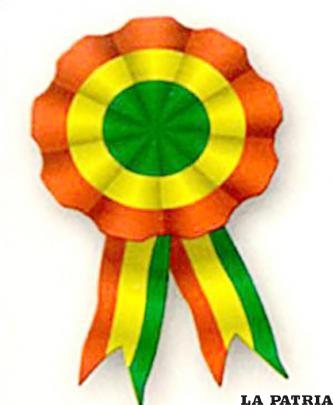 ESCARAPELA
Es un lazo plegado en círculo con los colores patrios, en el borde exterior está el rojo, en la parte central el amarillo y en el interior el verde. La cinta tiene una forma en V invertida en la que sobresale el rosetón.