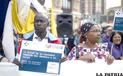 Manifestante sostiene un cartel que simula una tarjeta sanitaria durante una protesta contra los planes de restringir el acceso a la sanidad pública /REUTERS/Vincent West