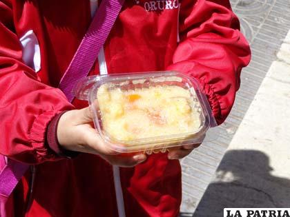 Una niña muestra la ensalada de frutas descompuesta