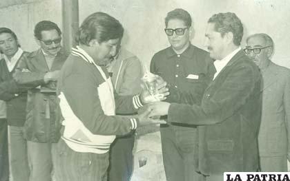 Enrique Pozo recibe el trofeo de campeón ante la mirada de Wilson Sandy