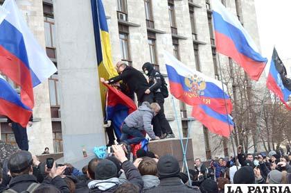 Manifestantes prorrusos retirando la bandera de Ucrania