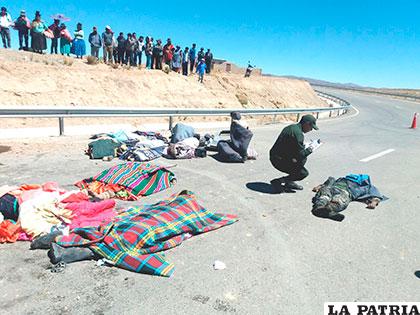 Los cuerpos de las víctimas del hecho yacen en la carretera, mientras policías realizan sus labores investigativas