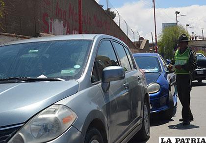 Un funcionario de Tránsito elabora una boleta de infracción para el motorizado estacionado indebidamente