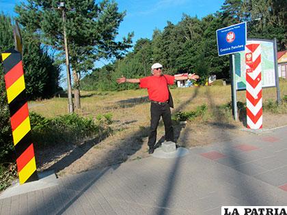 Victoruro Sepúlveda parado sobre el hito de la frontera Alemania-Polonia a orillas del Mar Báltico