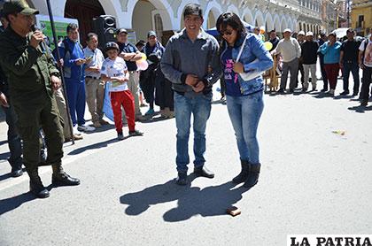 La pareja encuentra la billetera y se predispone a alzarla para conocer su contenido