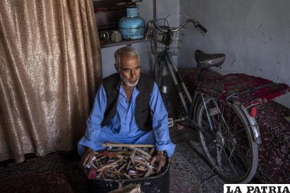 El lutier (fabricante de instrumentos) Mohammad Ibrahim Afzali fotografiado con pedazos de armonios rotos dentro de su taller en Kabul /AP PHOTO / Bernat Armangue