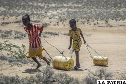 Dos niñas jalan contenedores con agua hacia sus casas desde un pozo en el pueblo de Lomoputh, en el norte de Kenia /AP Foto/Brian Inganga, Archivo