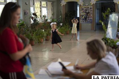 Dos niñas juegan mientras una mujer distribuye pastillas de yodo, por si se produce una fuga de radiación en la central nuclear de Zaporiyia /AP Foto/Leo Correa