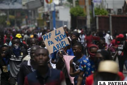 Un hombre sostiene un letrero con el mensaje â€œLa gente no te quiere Arielâ€, /AP Foto /Odelyn Joseph