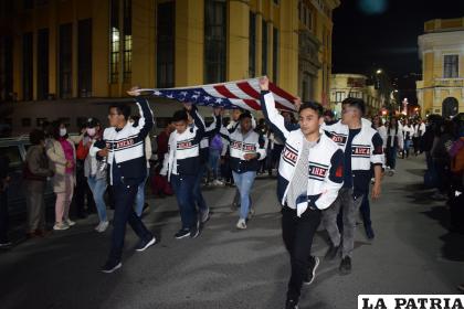 Muchachos de una promoción reciente llevan la bandera americana en brazos
