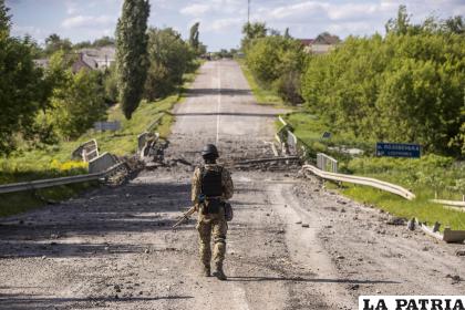 Soldado patrullando entre los restos de un puente cerca del campo de batalla en Járkov, en el Este de Ucrania /EFE