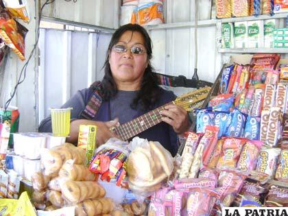 Ana Caballero, ejecuta el charango en su puesto de venta, demostrando que no hay edad para emprender alguna actividad