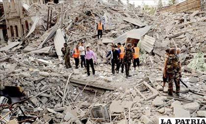 Varios policías y ciudadanos inspeccionan los daños causados en el lugar afectado por la explosión de tres coches bomba en Alepo (Siria) /EFE