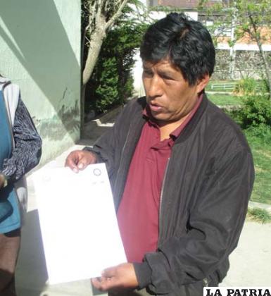 El padre de familia de la víctima muestra el certificado forense