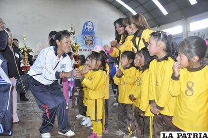 María Luz Véliz hace la entrega del trofeo de campeón en la disciplina de básquetbol