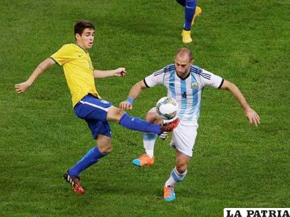 Oscar y Mascherano en la disputa del balón