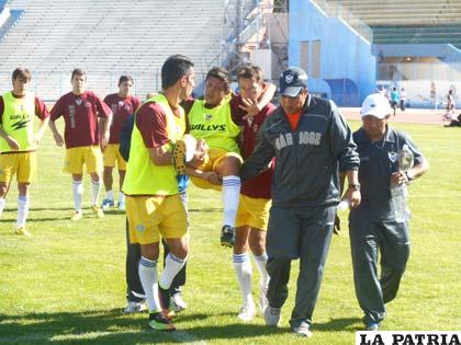 Lora sale del campo de juego ayudado por sus compañeros