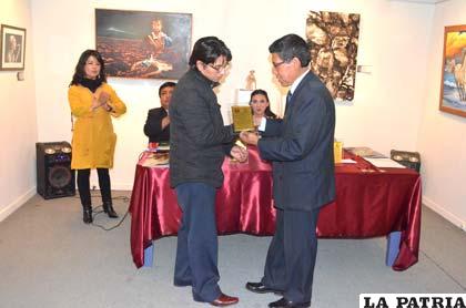 Fernando Cayola recibe de las manos de Grover Véliz su reconocimiento
