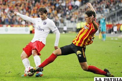Maxwell del PSG, intenta superar el marcaje de Chavarría del Lens