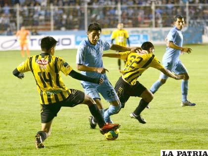 El orureño Saavedra jugador de Bolívar, intenta abrirse paso entre dos defensores