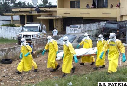 Voluntarios y profesionales en salud llevan a un paciente con ébola