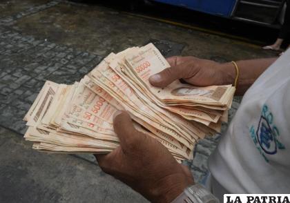 Un hombre cuenta billetes que estaban vigentes anteriormente, por el equivalente a un dólar /(AP Foto /Ariana Cubillos, archivo)