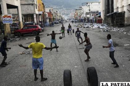 Jóvenes juegan al fútbol frente a comercios cerrados debido a una huelga general en Puerto Príncipe, Haití /AP Foto /Matias Delacroix