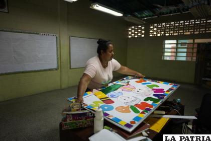 La maestra Yaisbet Espinosa, de 28 años, lleva un cartel de bienvenida a un salón de clases de la escuela Jerman Ubaldo Lira en Caracas /AP Foto /Ariana Cubillos
