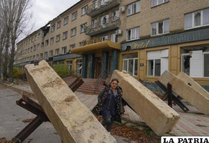 Una mujer camina entre obstáculos antitanques frente a un hotel en Bakhmut /AP Foto/Efrem Lukatsky