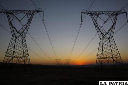 Sale el sol tras unas torres eléctricas en una imagen de archivo /EFE/Kim Ludbrook