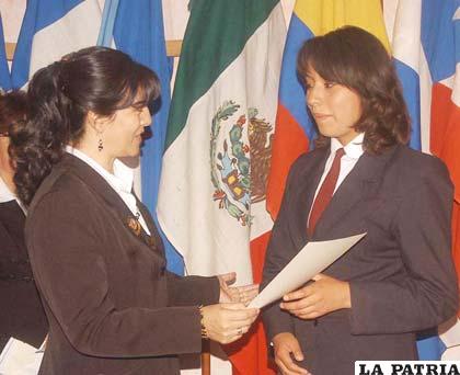 Alison Andrea Muñoz, ganadora del primer lugar en el Concurso sobre la vida y obra de Marcos Beltrán Ávila, recibe la distinción de una representante de la Mesa Redonda Panamericana