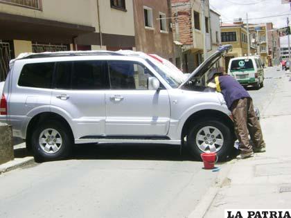 Lavando o arreglando el carro, pero a la vez bloqueando