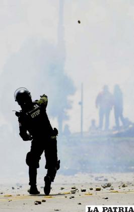Efectivo de la Policía lanza una granada de gas a los  manifestantes