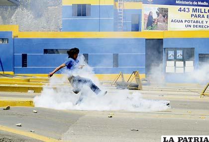 Estudiante de la Universidad Pública de El Alto (UPEA) patea una granada de gas lanzada por la policia
