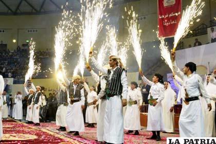 Varios hombres sostienen fuegos artificiales durante la boda masiva celebrada en Saná, Yemen