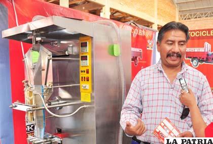 Edwin Santa Cruz muestra la máquina envasadora de agua