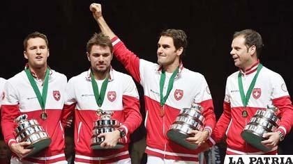 El equipo suizo que alcanzó la gloria en la Copa Davis, Federer levanta la mano derecha saludando a sus seguidores