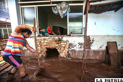 Una pareja intenta limpiar su casa anegada por el lodo /yucatan.com.mx