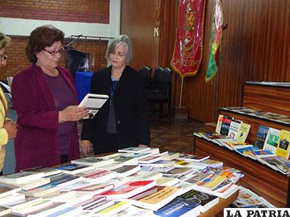 La rectora de la Unior, María Cortés, y la consejera Drake observan los libros de donación